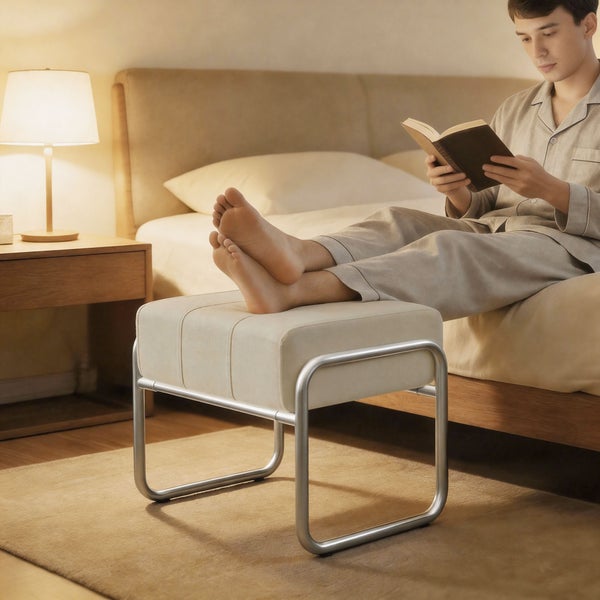 Mann liest Buch im Schlafzimmer mit Fußhocker