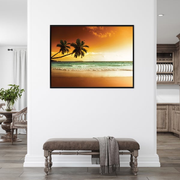Gerahmtes Wandbild mit Strandmotiv und Palmen bei Sonnenuntergang in einem modern eingerichteten Wohnraum mit Sitzbank.