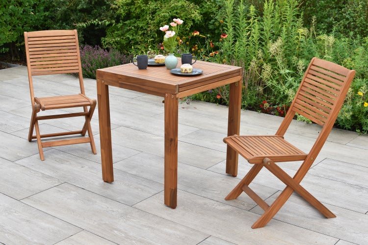 Quadratischer Gartentisch mit zwei Klappstühlen auf einer Terrasse