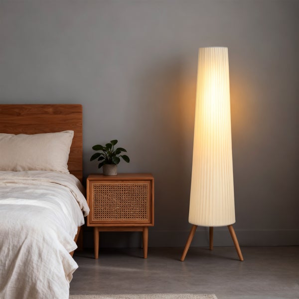 Moderne Stehleuchte mit plissiertem Stoffschirm und Holzstativ im Schlafzimmer neben Nachttisch und Holzbett.
