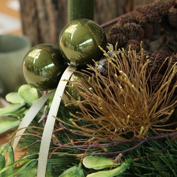 Dekoratives Gesteck mit Tannenzweigen, Kugeln und Zapfen als Weihnachtsschmuck