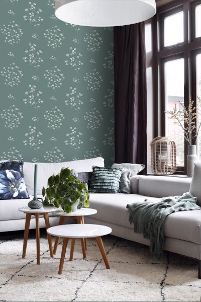 Wohnzimmer mit floral gemusterter Tapete, Sofa und Beistelltischen