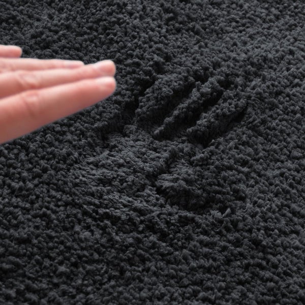 Detailaufnahme eines hochflorigen Teppichs mit Handabdruck