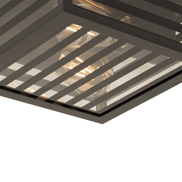 Nahaufnahme einer quadratischen schwarzen Deckenleuchte mit Metallrahmen und Lamellen sowie sichtbaren Leuchtmitteln hinter Glas.