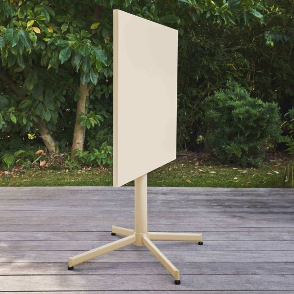 Beiger quadratischer Bistrotisch mit abklappbarer Tischplatte aus Metall auf einer Holzterrasse im Garten.