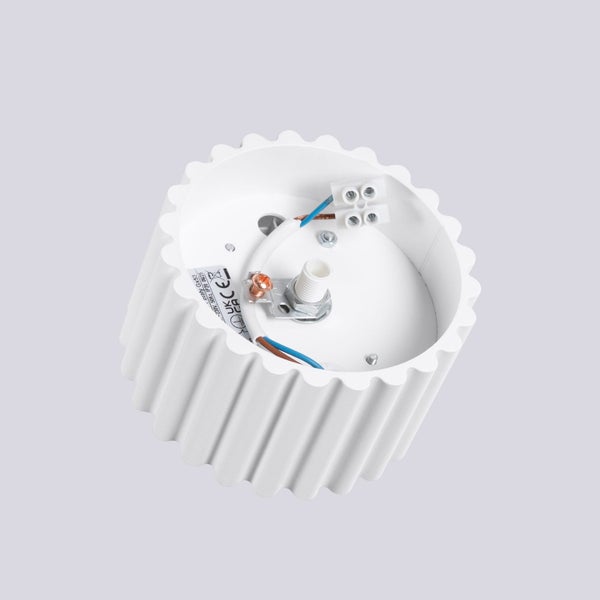 Innenansicht einer weißen zylindrischen Aufbauleuchte mit geriffeltem Gehäuse und elektrischen Anschlüssen