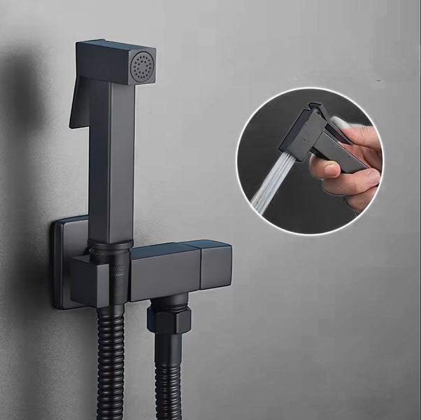 Schwarze Bidet-Handbrause im eckigen Design mit Wandhalterung und Schlauch, Detailansicht zeigt Wasserstrahl bei Benutzung.