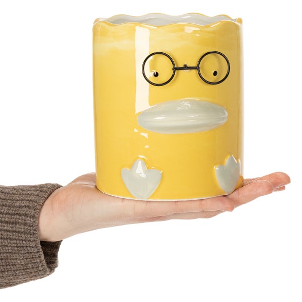 Gelber Übertopf in Entenform mit Brille auf einer Hand