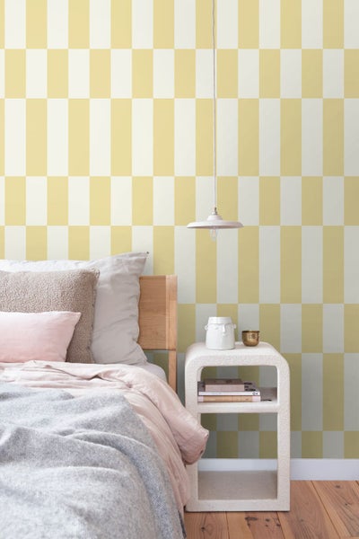 Vliestapete mit großflächigem geometrischem Rechteckmuster in einem hellen Schlafzimmer mit Holzbett und Nachttisch.