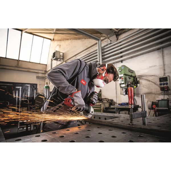 Handwerker mit Schutzbrille und Atemschutz beim Arbeiten mit einem Flex Winkelschleifer an einem Metallstück in der Werkstatt.