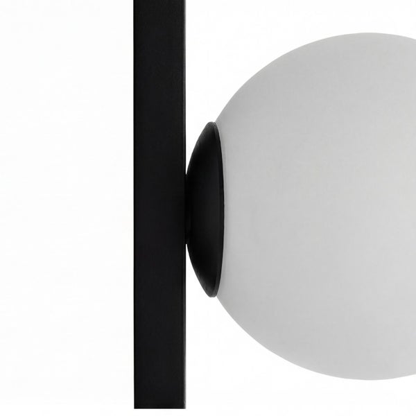Nahaufnahme einer modernen Lampe mit weißer Glaskugel und schwarzem Metallstab.