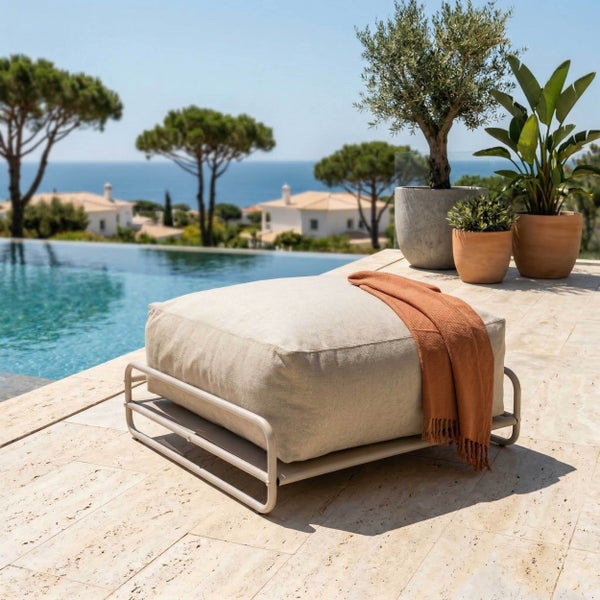 Moderner Outdoor-Hocker mit Metallgestell und beigem Stoffkissen, mit terrakottafarbener Decke, auf einer Steinterrasse am Pool.