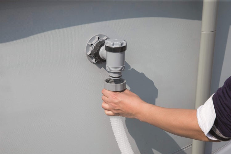 Person schließt einen Schwimmbadschlauch an ein Schwimmbecken an