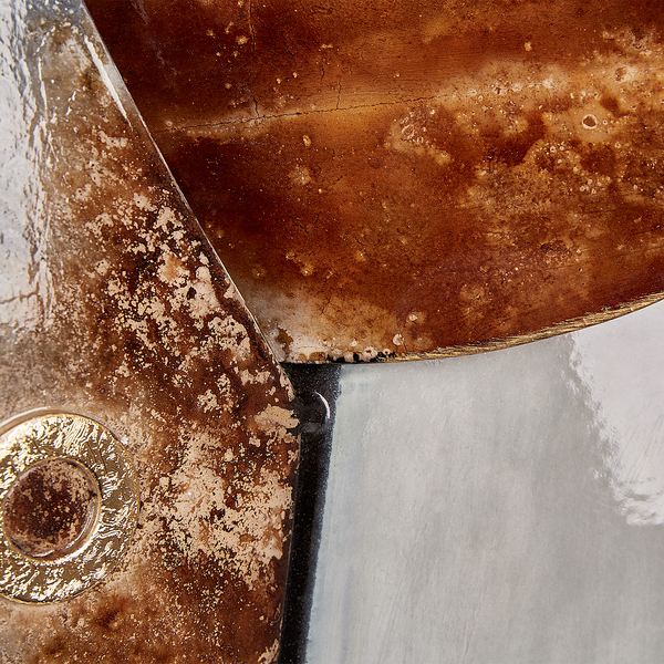 Nahaufnahme einer Wanddekoration mit strukturierten Metalloberflächen in Rostoptik und kreisförmigem Detail.