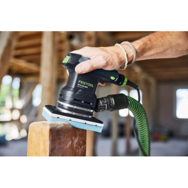 Eine Person schleift einen Holzbalken mit einem Festool RTS 400 REQ Rutscher mit angeschlossenem Absaugschlauch.
