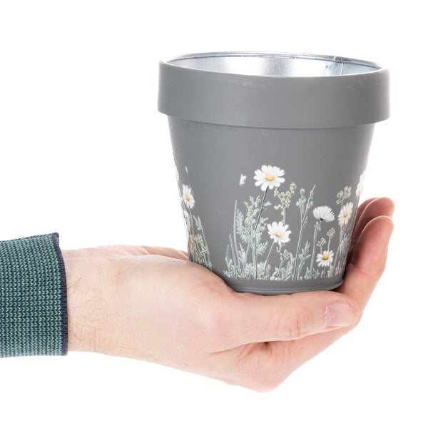 Grauer Metall-Blumentopf mit Gänseblümchenmotiv, gehalten in einer Hand zur Darstellung der Größe.