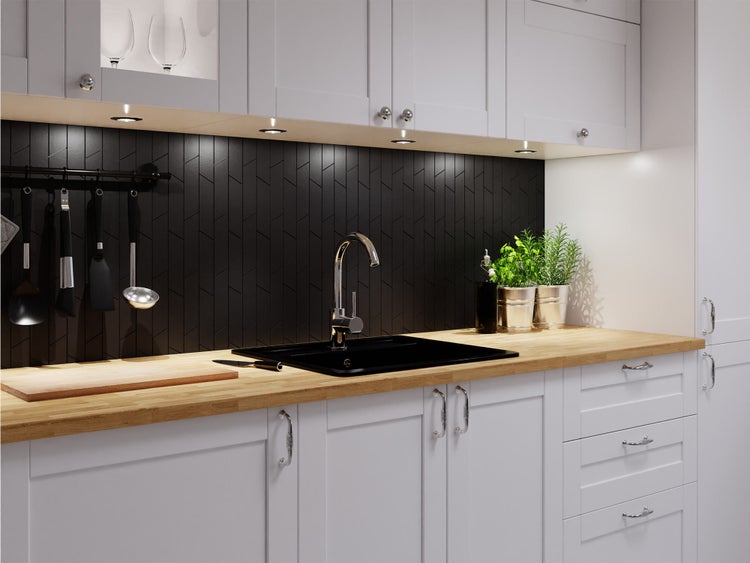 Moderne Küche mit hellen Schränken, Holz-Arbeitsplatte, schwarzer Spüle und dunkler Rückwand mit Fischgrätenmuster.