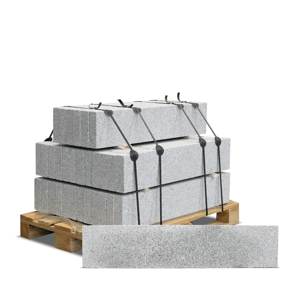 Granitsteine auf einer Holzpalette, mit Bändern gesichert, ein einzelner Stein im Vordergrund.