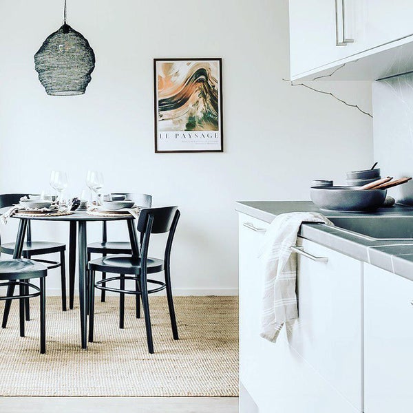 Esszimmer mit Esstisch, Stühlen, Lampe und Dekorationsartikeln in einem hellen Raum.