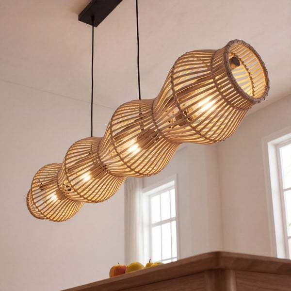 Vierflammige Pendelleuchte aus Rattan-Geflecht mit wellenförmiger Silhouette, hängend über einem Tisch in einem hellen, modernen Innenraum.
