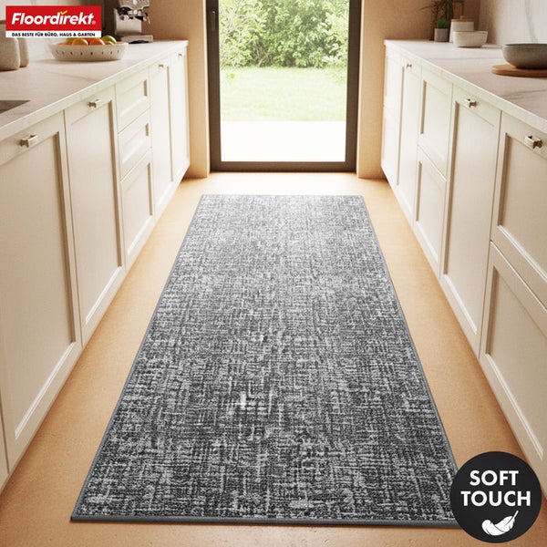Küchenszene mit grauem Teppichläufer zwischen weißen Küchenschränken und Terrassentür