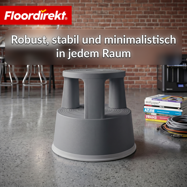 Grauer Rollhocker aus Kunststoff in einem modernen Arbeitsraum vor einer Backsteinwand. Floordirekt Logo.