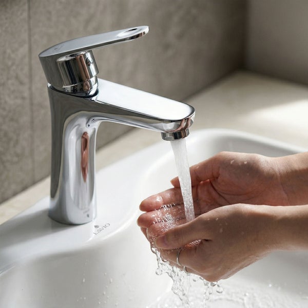 Einhebel-Waschtischmischer in Chrom mit fließendem Wasser über Händen an einem weißen Waschbecken.