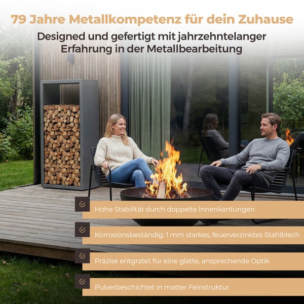 Ein Mann und eine Frau sitzen an einer Feuerschale auf einer Holzterrasse neben einem Kaminholzregal aus Metall.