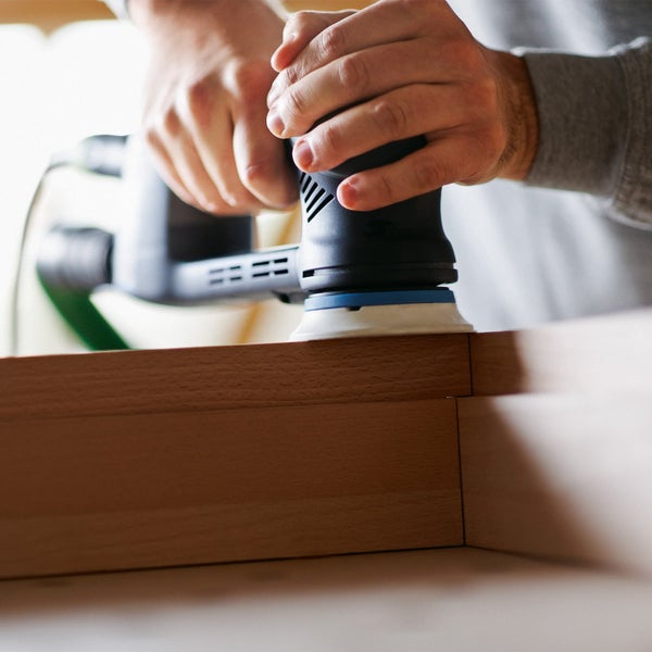 Eine Person schleift Holz mit einem Exzenterschleifer.