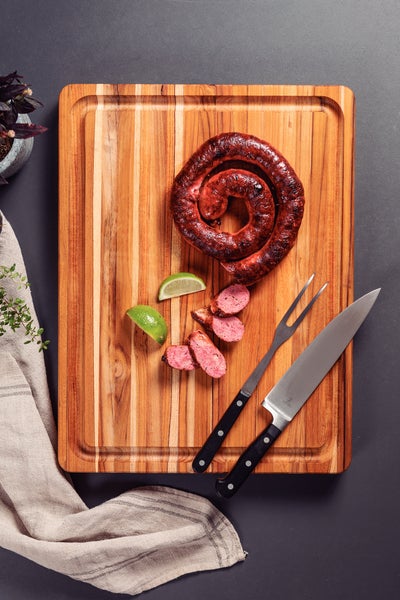 Gegrillte Wurst auf Holzbrett mit Messer und Gabel