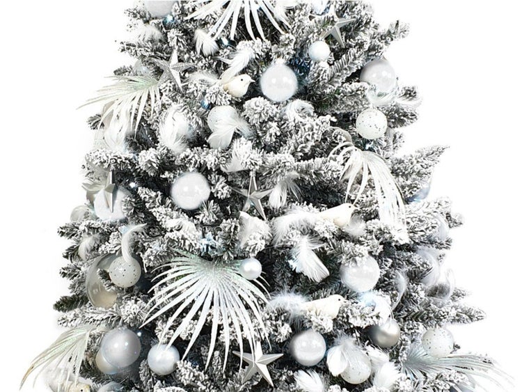 Künstlicher, verschneiter Weihnachtsbaum mit dekorativen Kugeln, Sternen, Federn und Vogelornamenten für eine festliche Dekoration.