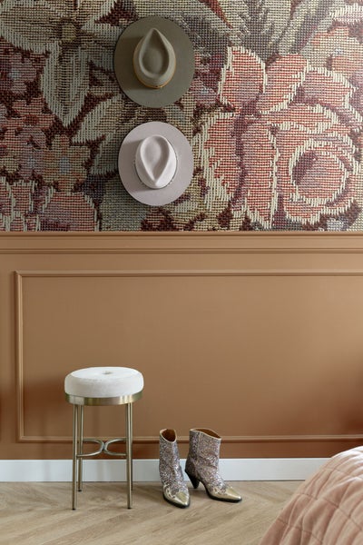 Raumansicht mit floraler Tapete, zwei Hüten, Hocker und Stiefeln