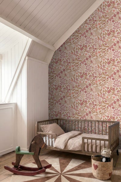 Vliestapete mit floralem Muster in einem hellen Kinderzimmer mit Holzbett und Schaukelpferd.