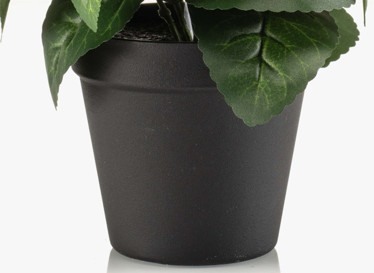 Dunkler Pflanztopf aus Kunststoff mit den grünen Blättern einer Kunstpflanze.