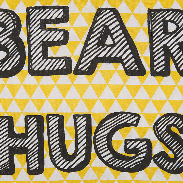 Nahaufnahme eines Stoffes mit dem Schriftzug BEAR HUGS und einem Muster aus kleinen Dreiecken.