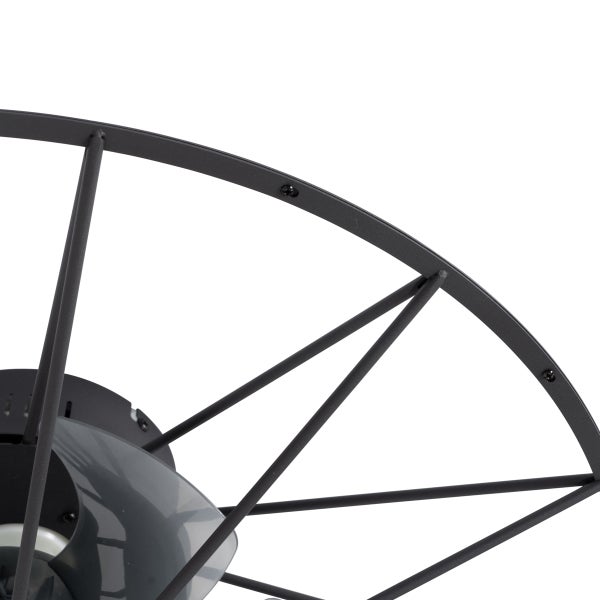 Detailansicht eines Deckenventilators mit rundem Metallkäfig und dunklen Flügeln aus Metall und Kunststoff.