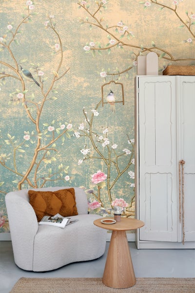 Wohnzimmer mit Sessel, Beistelltisch und Wandtapete mit Vogel- und Blumenmuster