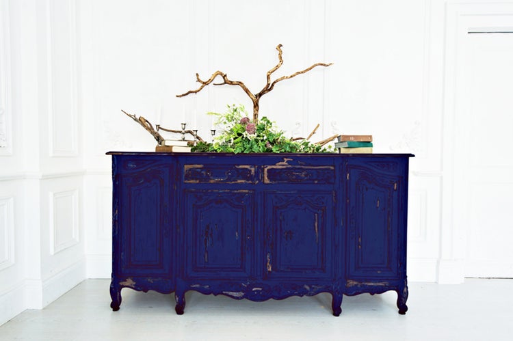 Antiker blauer Holzschrank mit floralen Akzenten und Büchern als Dekoration