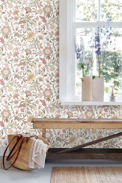 Helle Raumszene mit floral gemusterter Tapete an der Wand, einer rustikalen Holzbank und Blumenvasen auf dem Fensterbrett.