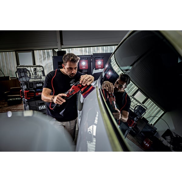 Ein Handwerker poliert mit einer elektrischen Exzenterpoliermaschine von Flex die Karosserie eines Autos in einer Werkstatt.