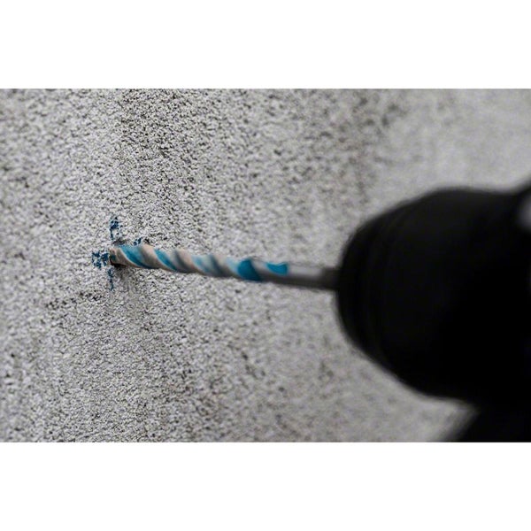 Nahaufnahme eines Bohrers, der in eine graue Betonwand bohrt