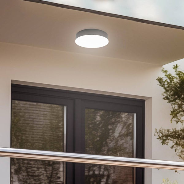 Runde LED-Außen-Deckenleuchte an einer Decke über einer dunklen Fenstertür montiert.