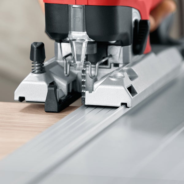 Stichsäge mit Führungsschiene beim Sägen eines Holzbrettes