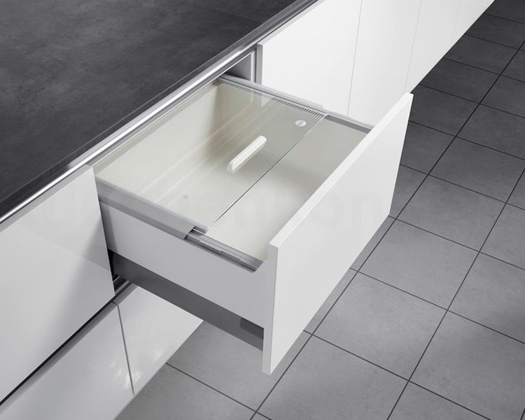 Geöffnete Küchenschublade mit integriertem Abfalleimer und transparentem Deckel in einer modernen weißen Einbauküche.