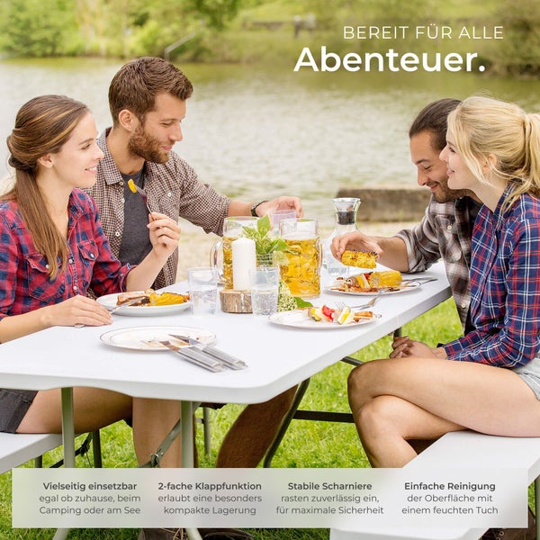 Helle Außenszene: Vier Personen an einer weißen, klappbaren Camping-Sitzgruppe aus Kunststoff und Metall beim Essen an einem See.