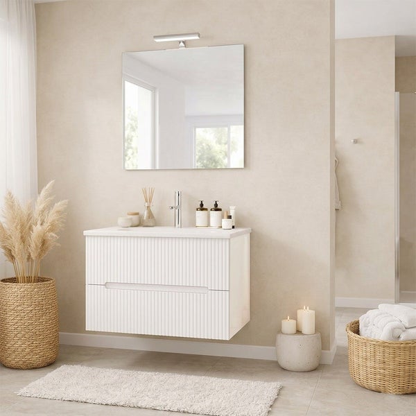 Modernes Badezimmer mit Waschtischunterschrank mit Rillenfront, Wandspiegel und Armatur vor heller Wand in wohnlichem Ambiente.
