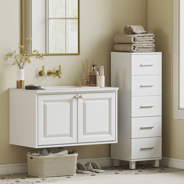 Helles, organisiertes Badezimmer mit weißem Hänge-Waschtischunterschrank, hohem weißem Schubladenschrank, goldfarbenen Armaturen und Spiegel.