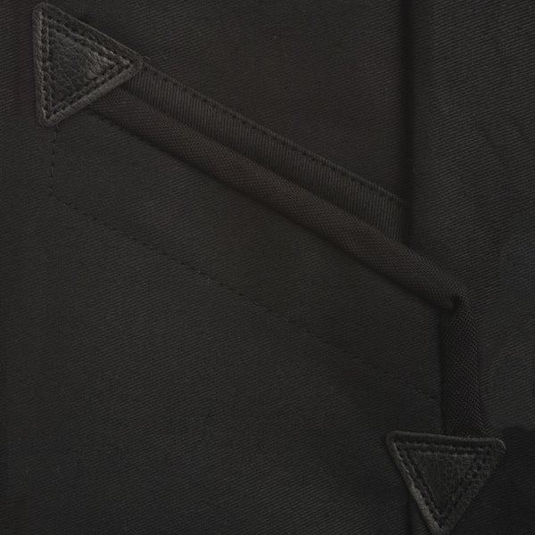Detailansicht einer Tasche an Arbeitsbekleidung mit dreieckigen Lederverstärkungen an den Ecken.
