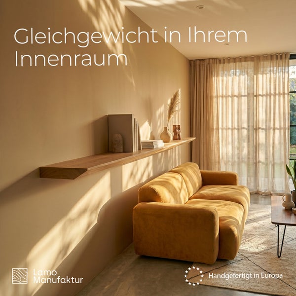 Modernes Wohnzimmer mit langem Holz-Wandregal über Sofa, helles Licht. Lamo Manufaktur Logo. Handgefertigt in Europa.