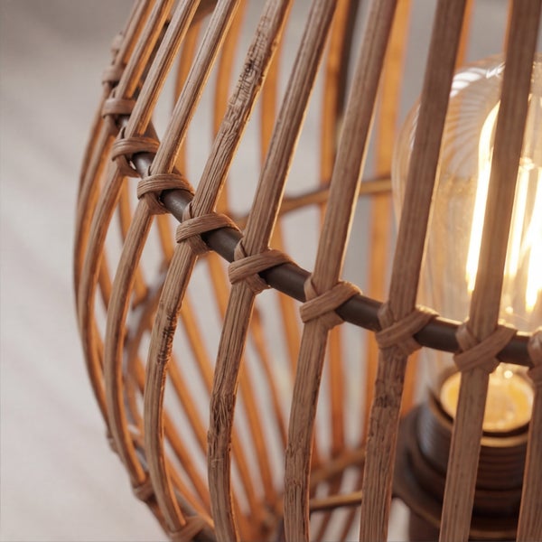 Detailaufnahme einer Leuchte mit Rattangeflecht und einem brennenden Leuchtmittel im Vintage-Stil.